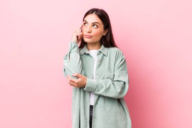 Yoğunlaşmış bakışları olan genç ve güzel bir kadın şüpheli bir ifadeyle yukarı ve yana bakıyor.