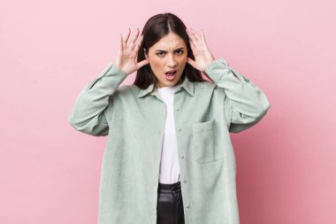 Genç, güzel bir kadın panik ya da öfke içinde bağırıyor. Şok olmuş, korkmuş ya da öfkeli. Elleri başının yanında.