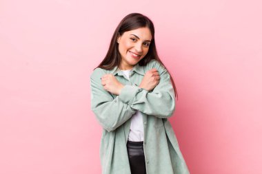 Genç, güzel bir kadın, neşeli bir şekilde gülümsüyor ve kutluyor. Yumruklarını sıkmış, kollarını kavuşturmuş, mutlu ve pozitif hissediyor.