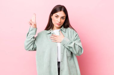 Genç, güzel bir kadın mutlu, kendinden emin ve güvenilir görünüyor. Gülümsüyor ve zafer işareti gösteriyor. Olumlu bir tavırla.