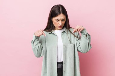 Genç, güzel bir kadın şoke olmuş, ağzı açık ve şaşırmış, inançsızlık ve şaşkınlık içinde bakıyor ve onu işaret ediyor.