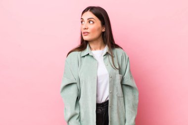 Genç, güzel bir kadın şaşkın, mutlu, şaşkın ve şaşırmış hissediyor, ağzı açık bir şekilde yana bakıyor.