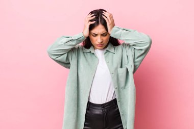 Genç ve güzel bir kadın stresli ve hayal kırıklığına uğramış hissediyor, elele tutuşuyor, yorgun, mutsuz ve migren ağrısı çekiyor.