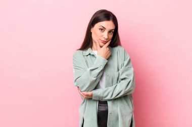 Genç ve güzel bir kadın ciddi, düşünceli ve güvensiz görünüyor. Bir kolu çapraz, eli çenesinde, seçenekleri değerlendiriyor.