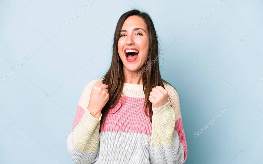 young adult pretty woman shouting triumphantly, laughing and feeling happy and excited while celebrating success