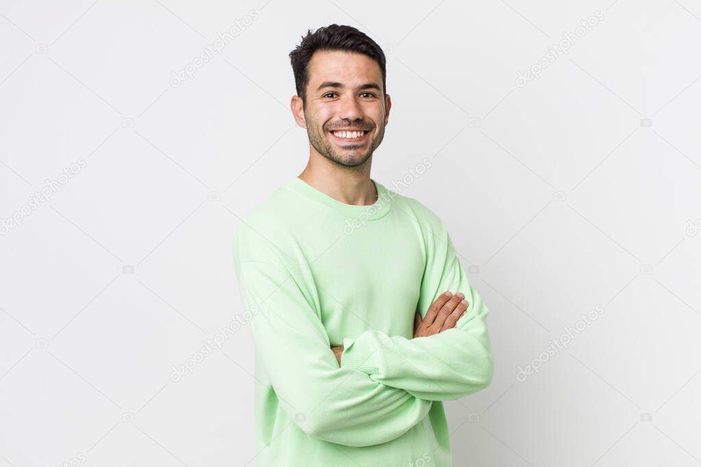 young handsome hicpanic man smiling to camera with crossed arms and a happy, confident, satisfied expression, lateral view