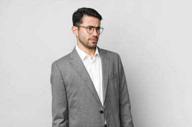 Genç, Latin bir adam üzgün, üzgün ya da kızgın hissedip yan tarafa bakıyor. iş kavramı