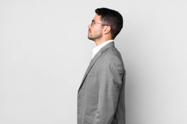 Profil görünümlü genç, İspanyol bir adam hayal kuruyor, hayal görüyor ya da hayal görüyor. iş kavramı