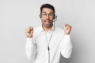 Genç, İspanyol bir adam şok olmuş, gülüyor ve başarıyı kutluyor. tele pazarlamacı kavramı