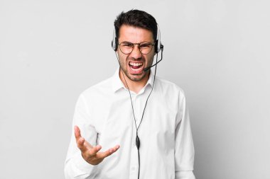 Genç, İspanyol bir adam sinirli, sinirli ve hayal kırıklığına uğramış görünüyor. tele pazarlamacı kavramı