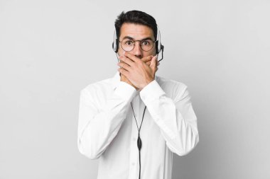 Genç, İspanyol bir adam şok olmuş bir şekilde ağzını eliyle kapatıyor. tele pazarlamacı kavramı