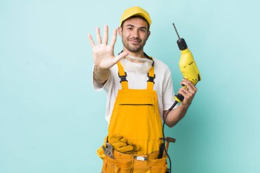 Genç, İspanyol bir adam gülümsüyor ve arkadaş canlısı görünüyor. Beş numarayı gösteriyor. işçi ve sondaj kavramı