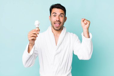 Genç, İspanyol bir adam şok olmuş, gülüyor ve başarıyı kutluyor. traş konsepti