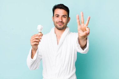 Genç, İspanyol bir adam gülümsüyor ve arkadaş canlısı görünüyor, üç numarayı gösteriyor. traş konsepti