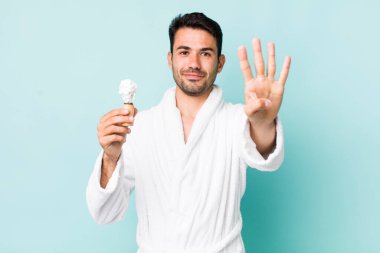 Genç, İspanyol bir adam gülümsüyor ve arkadaş canlısı görünüyor, dört numarayı gösteriyor. traş konsepti