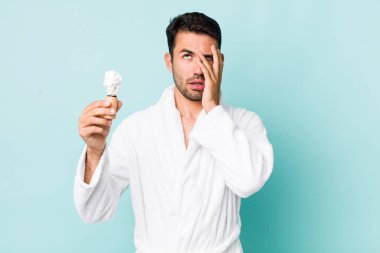 young adult hispanic man feeling bored, frustrated and sleepy after a tiresome. shaving concept