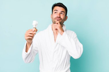 young adult hispanic man thinking, feeling doubtful and confused. shaving concept