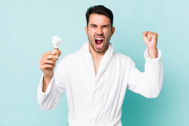 young adult hispanic man shouting aggressively with an angry expression. shaving concept