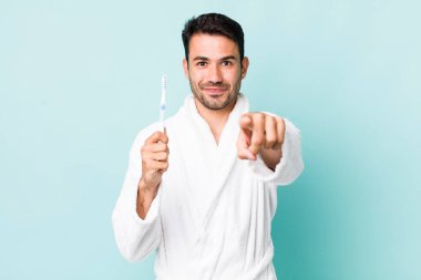 young adult hispanic man pointing at camera choosing you. toothbrush concept
