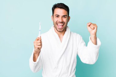 young adult hispanic man feeling shocked,laughing and celebrating success. toothbrush concept