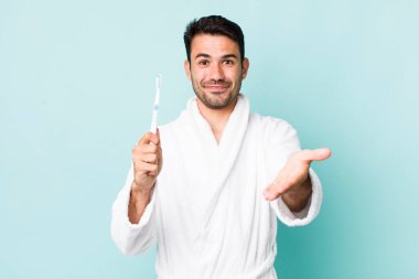 young adult hispanic man smiling happily with friendly and  offering and showing a concept. toothbrush concept