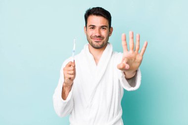 young adult hispanic man smiling and looking friendly, showing number four. toothbrush concept