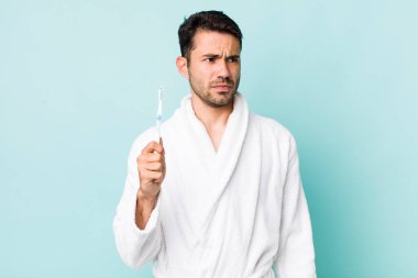 young adult hispanic man feeling sad, upset or angry and looking to the side. toothbrush concept