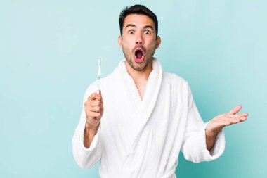 young adult hispanic man amazed, shocked and astonished with an unbelievable surprise. toothbrush concept