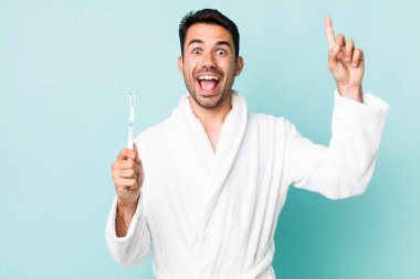 young adult hispanic man feeling like a happy and excited genius after realizing an idea. toothbrush concept