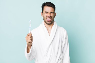 young adult hispanic man feeling disgusted and irritated and tongue out. toothbrush concept
