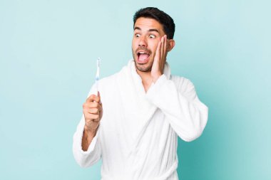 young adult hispanic man feeling happy, excited and surprised. toothbrush concept