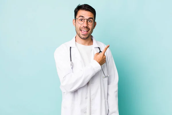 Young Adult Hispanic Man Looking Excited Surprised Pointing Side Physician — Stockfoto
