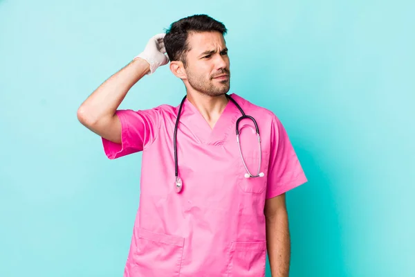 Young Adult Hispanic Man Feeling Puzzled Confused Scratching Head Veterinarian — Stockfoto