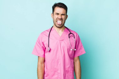 young adult hispanic man feeling disgusted and irritated and tongue out. veterinarian concept