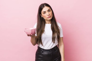 young pretty woman feeling puzzled and confused. empty bowl concept