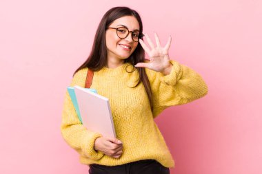 young pretty woman smiling and looking friendly, showing number five. university student concept