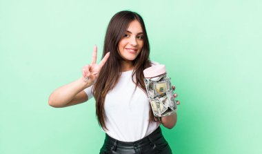 Genç, güzel bir bayan gülümsüyor ve iki numarayı gösteriyor. kaydetme kavramı