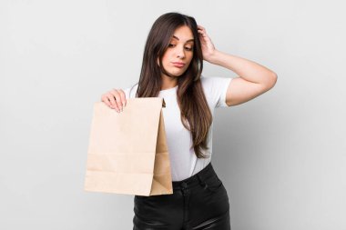 young pretty woman smiling happily and daydreaming or doubting. take away food concept