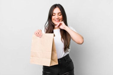 young pretty woman smiling with a happy, confident expression with hand on chin. take away food concept