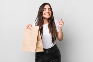 young pretty woman feeling shocked,laughing and celebrating success. take away food concept