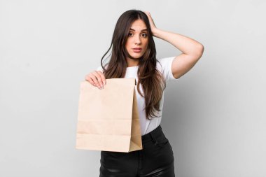 young pretty woman feeling stressed, anxious or scared, with hands on head. take away food concept