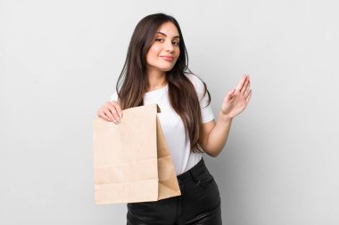 young pretty woman smiling happily, waving hand, welcoming and greeting you. take away food concept