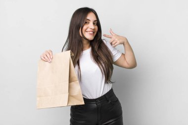 young pretty woman smiling confidently pointing to own broad smile. take away food concept