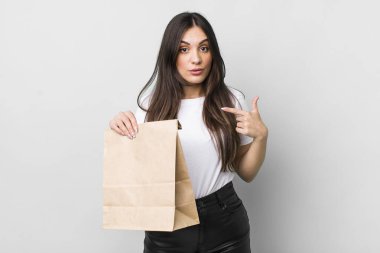 young pretty woman looking shocked and surprised with mouth wide open, pointing to self. take away food concept