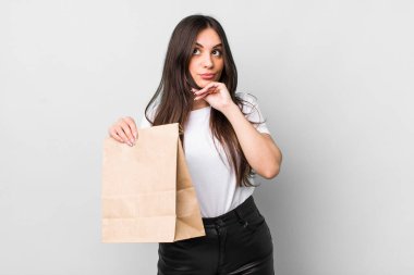 young pretty woman thinking, feeling doubtful and confused. take away food concept