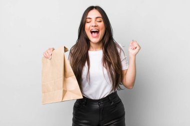 young pretty woman shouting aggressively with an angry expression. take away food concept