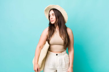 young pretty woman on profile view thinking, imagining or daydreaming. summer and hat concept