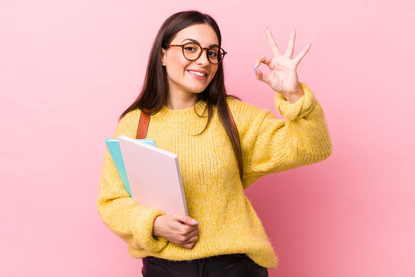 young pretty woman feeling happy, showing approval with okay gesture. university student concept