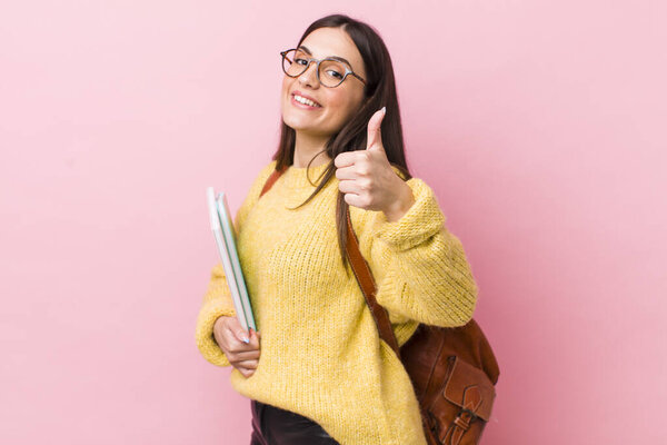 young pretty woman feeling proud,smiling positively with thumbs up. university student concept