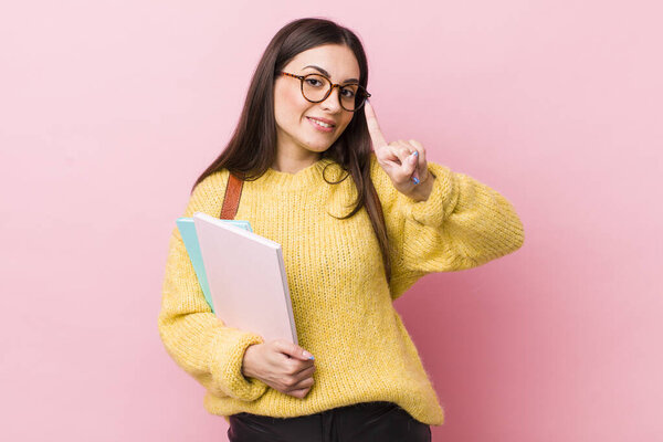 young pretty woman smiling and looking friendly, showing number one. university student concept